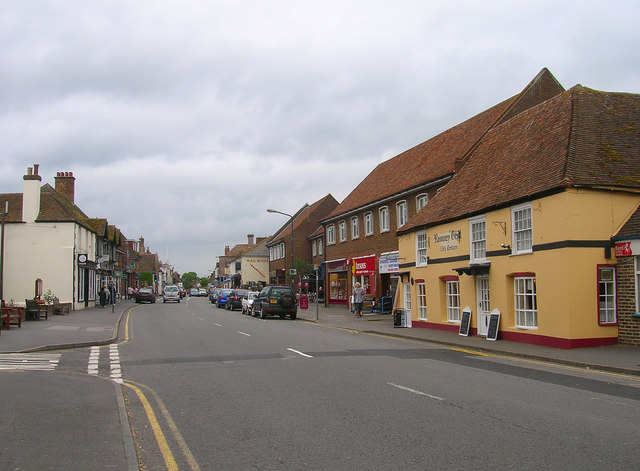 A bustling UK high street with shoppers and diverse storefronts, reflecting buoyant local economies.