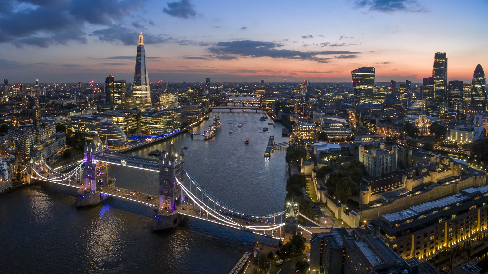 Modern London skyline at dusk, showcasing the city's financial district with illuminated skyscrapers and the River Thames.
