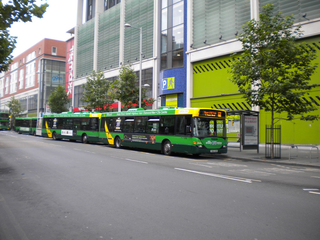 Exterior of a modern purpose-built student accommodation building in a vibrant UK city, with students entering and exiting.