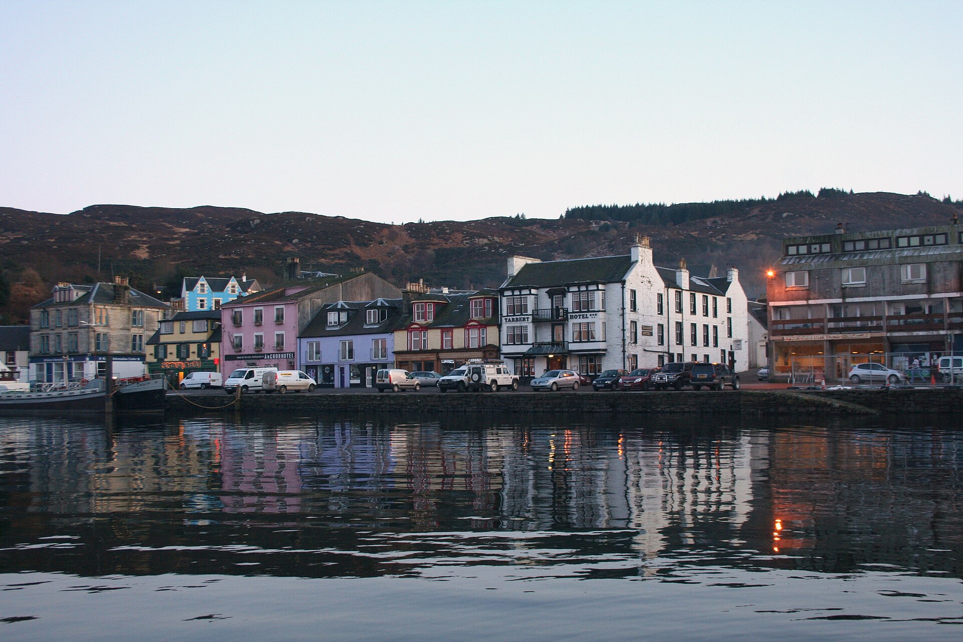 Hotel buildings beside a busy UK harbour with boats and visitors
